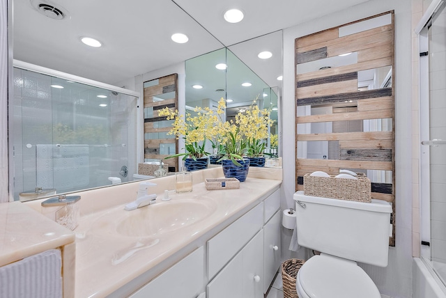 full bathroom with combined bath / shower with glass door, toilet, and vanity with extensive cabinet space