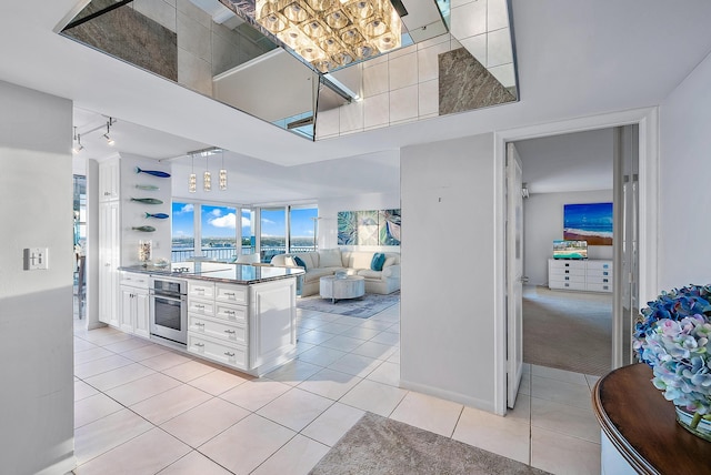 kitchen featuring oven, white cabinets, track lighting, and light colored carpet