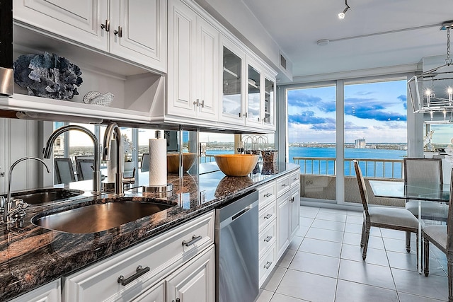 kitchen with dark stone counters, dishwasher, white cabinets, and a water view