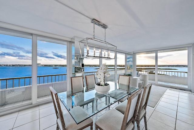 dining room with light tile floors, a chandelier, and a water view