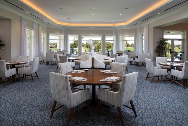 dining space with plenty of natural light and a tray ceiling