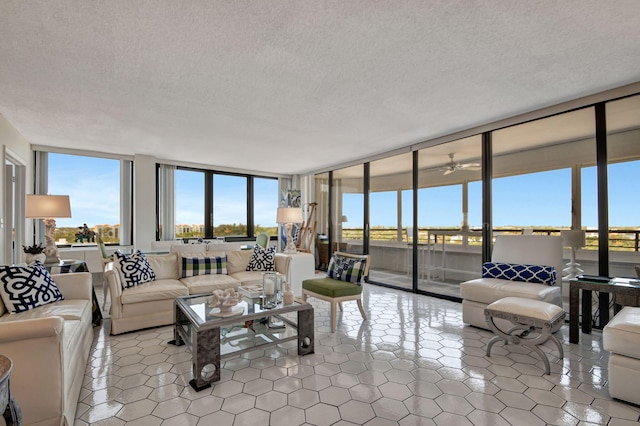 living room with a wall of windows, a textured ceiling, and tile patterned floors