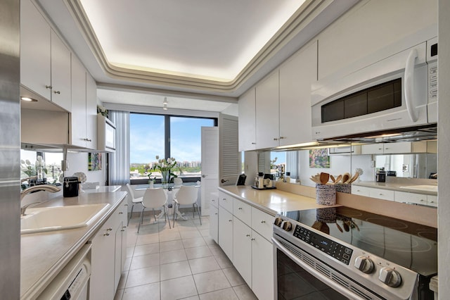 kitchen featuring white appliances, white cabinets, sink, and a raised ceiling