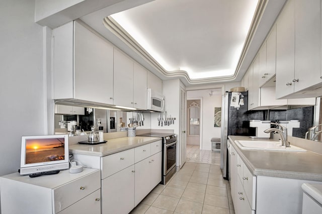 kitchen featuring light tile patterned floors, a raised ceiling, white microwave, stainless steel electric range oven, and light countertops