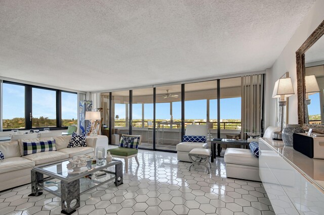 living room with tile floors, a textured ceiling, and a wall of windows