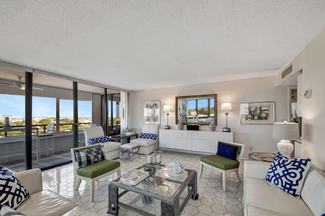 living area featuring light tile patterned floors, a ceiling fan, visible vents, and a textured ceiling