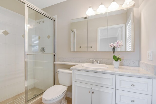 bathroom featuring vanity, toilet, and an enclosed shower