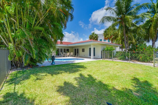 rear view of property with a fenced in pool, a yard, and a patio area