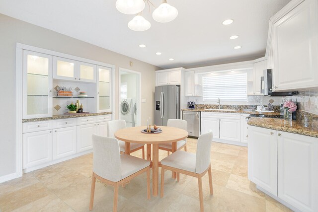 kitchen with independent washer and dryer, white cabinetry, tasteful backsplash, stainless steel appliances, and sink