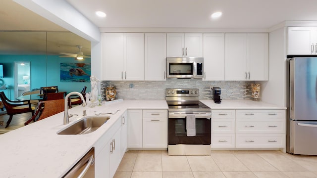 kitchen with white cabinetry, sink, ceiling fan, stainless steel appliances, and tasteful backsplash