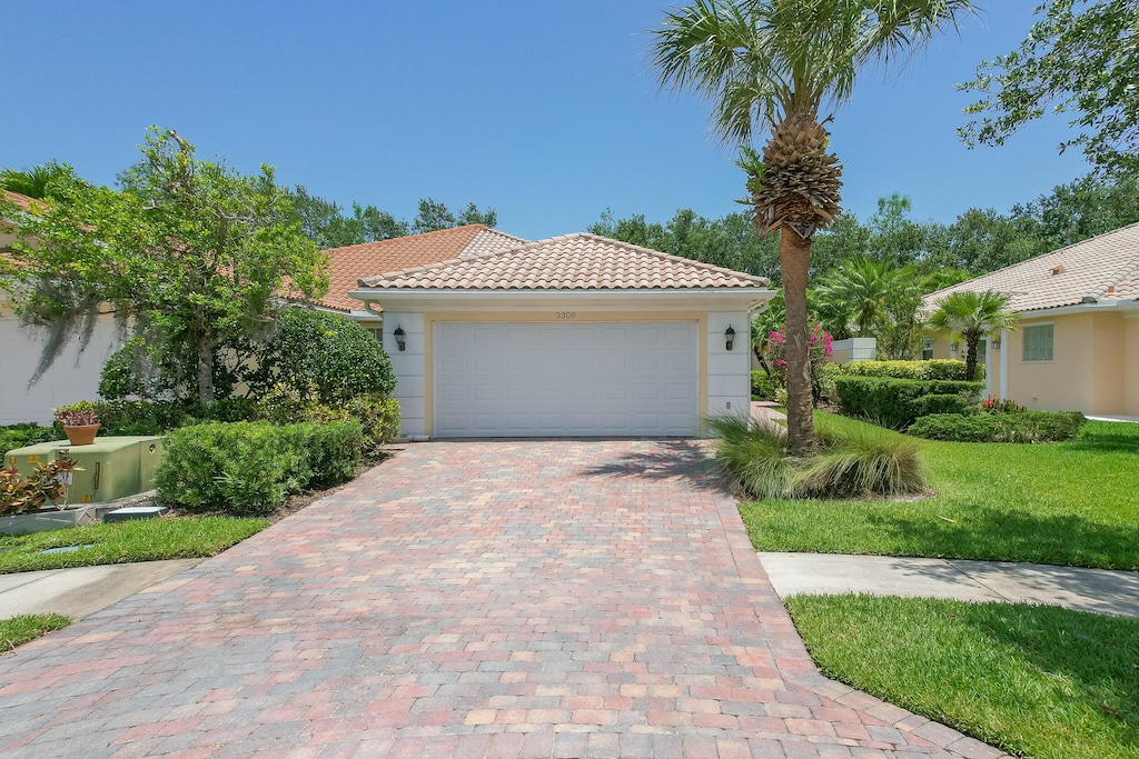 mediterranean / spanish-style home featuring a front lawn and a garage