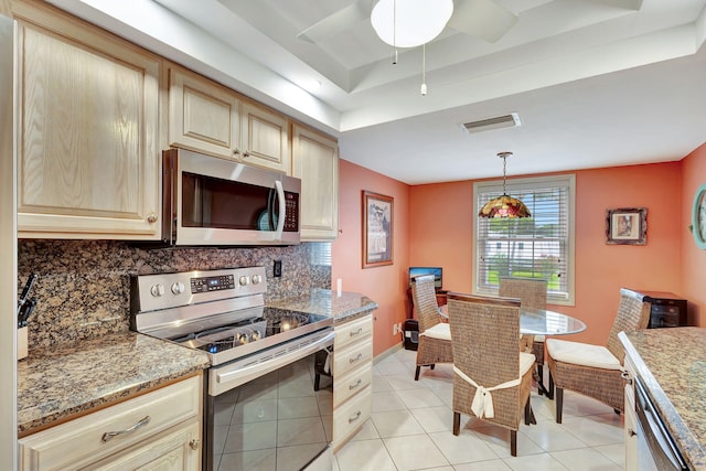 kitchen featuring stainless steel appliances, a raised ceiling, ceiling fan, and light tile floors