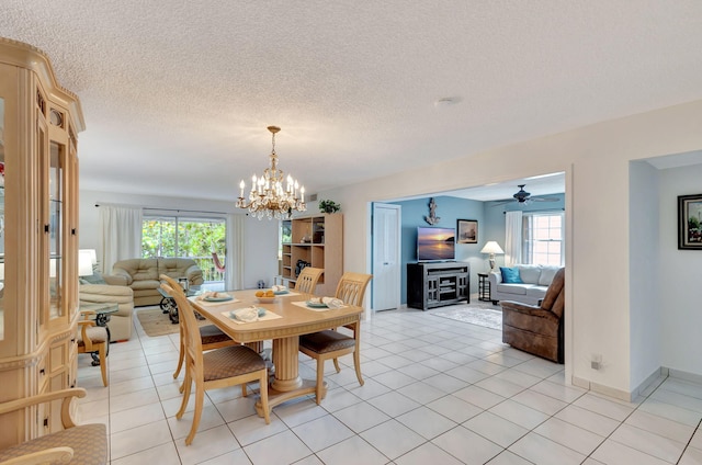 tiled dining room with ceiling fan with notable chandelier, a healthy amount of sunlight, and a textured ceiling