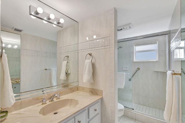 bathroom featuring walk in shower, tile floors, tile walls, large vanity, and toilet