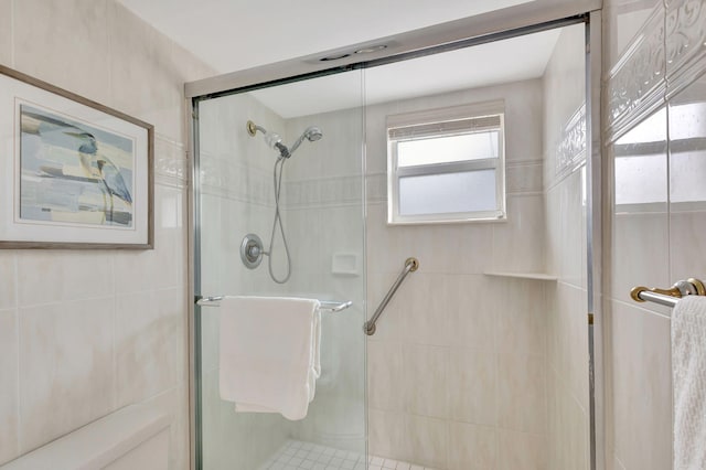 bathroom featuring a shower with door and tile walls