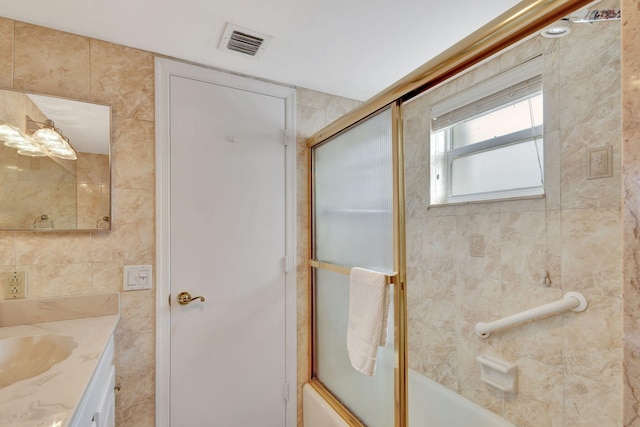 bathroom with tile walls, shower / bath combination with glass door, and vanity