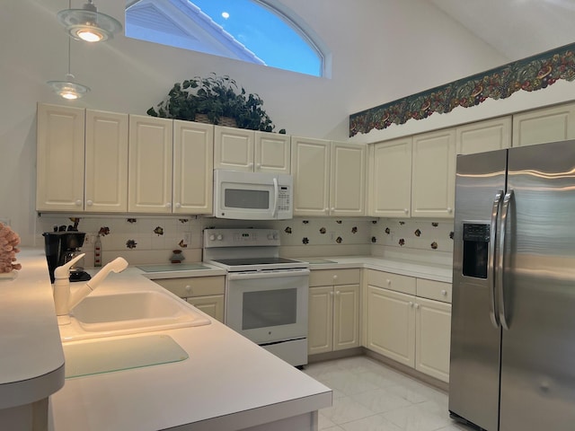 kitchen with light tile floors, high vaulted ceiling, white appliances, tasteful backsplash, and decorative light fixtures