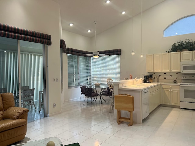 kitchen with high vaulted ceiling, kitchen peninsula, white appliances, ceiling fan, and a breakfast bar