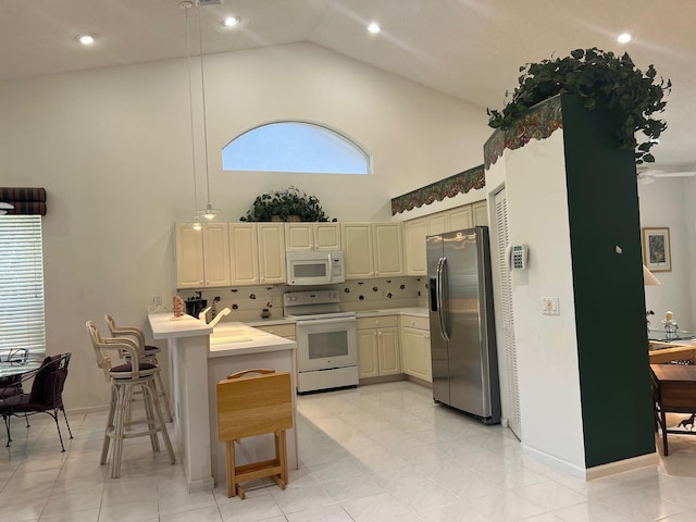 kitchen with a kitchen breakfast bar, white appliances, tasteful backsplash, and light tile flooring