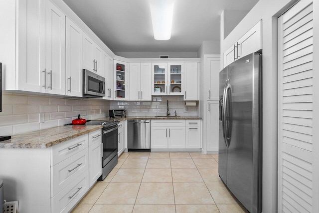 kitchen with light stone countertops, white cabinetry, appliances with stainless steel finishes, and tasteful backsplash