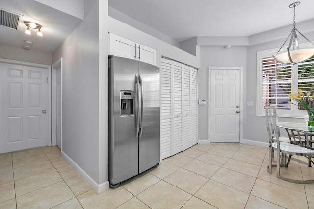 kitchen featuring white cabinets, stainless steel refrigerator with ice dispenser, decorative light fixtures, and light tile patterned floors