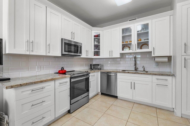 kitchen featuring white cabinets, light stone counters, sink, and stainless steel appliances