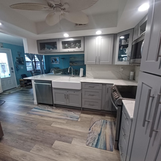 kitchen featuring light countertops, appliances with stainless steel finishes, gray cabinets, and glass insert cabinets