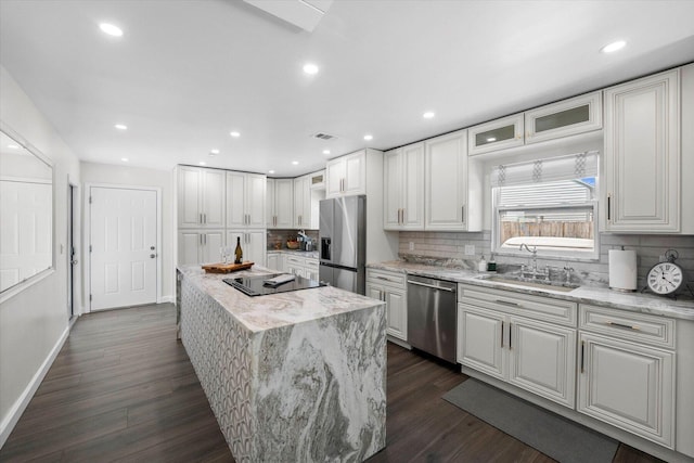 kitchen featuring appliances with stainless steel finishes, dark wood-type flooring, a kitchen island, and tasteful backsplash