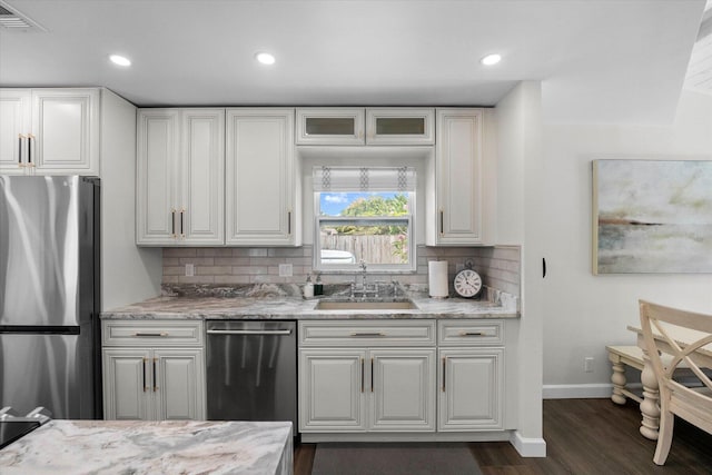 kitchen featuring appliances with stainless steel finishes, dark wood-type flooring, sink, and light stone countertops