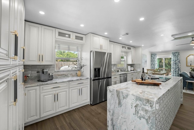 kitchen with stainless steel appliances, dark wood-type flooring, white cabinets, and plenty of natural light