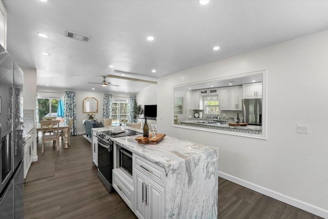 kitchen with dark hardwood / wood-style flooring, tasteful backsplash, ceiling fan, white cabinetry, and stainless steel appliances