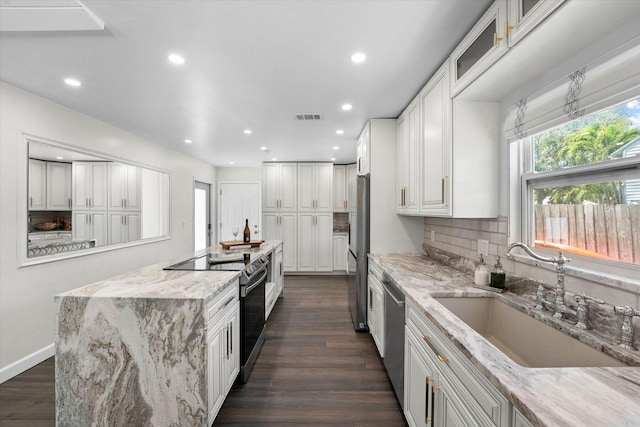 kitchen with sink, dark hardwood / wood-style floors, light stone countertops, and appliances with stainless steel finishes