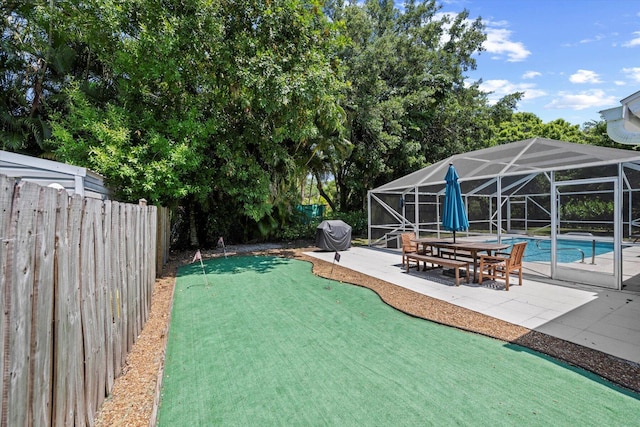 view of yard with glass enclosure, a patio, and a fenced in pool