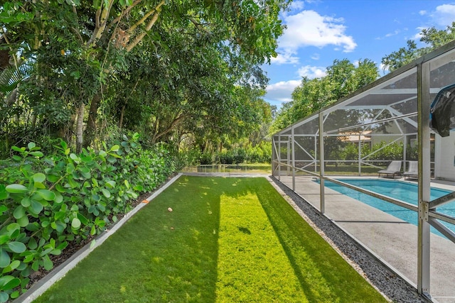 view of yard with glass enclosure and a patio