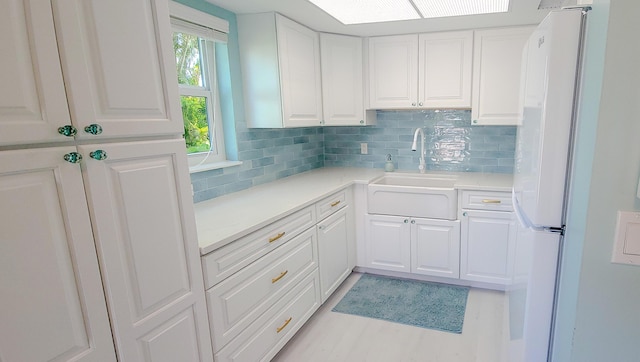 kitchen with backsplash, white cabinetry, sink, and white refrigerator