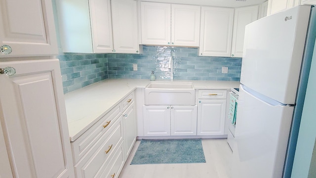 kitchen with white cabinets, white refrigerator, and backsplash