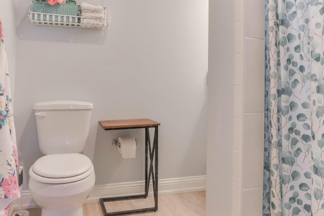 bathroom with hardwood / wood-style flooring, toilet, and a shower with shower curtain