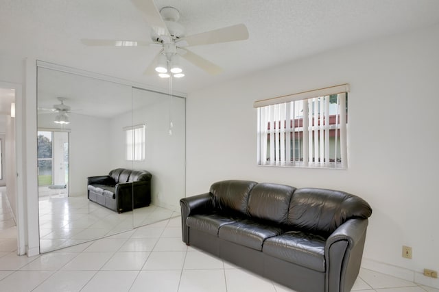 living room with light tile patterned flooring, ceiling fan, and a textured ceiling