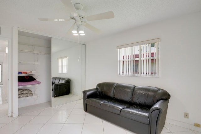 living room with a textured ceiling, light tile patterned floors, and ceiling fan