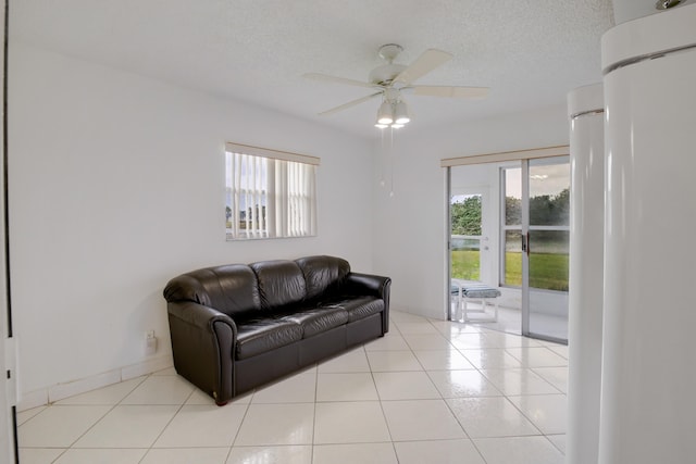 living room featuring ceiling fan, light tile patterned floors, and a textured ceiling