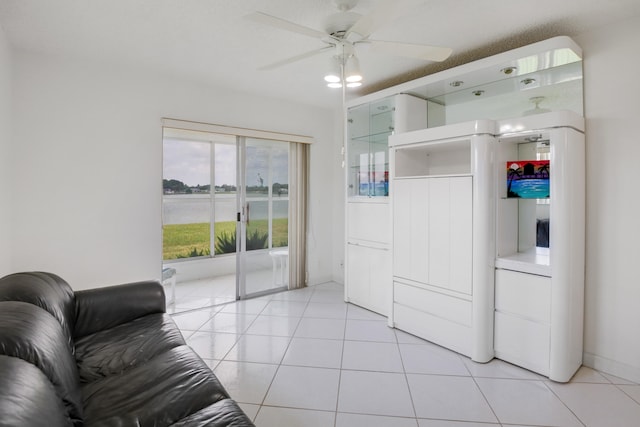 living room with ceiling fan, light tile patterned flooring, and a water view