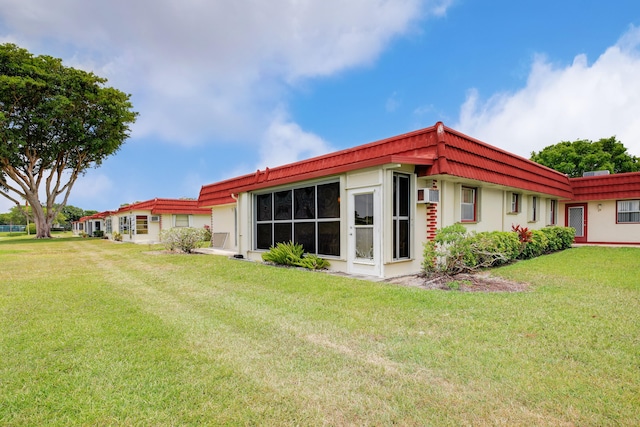 back of property with a yard and a wall mounted air conditioner