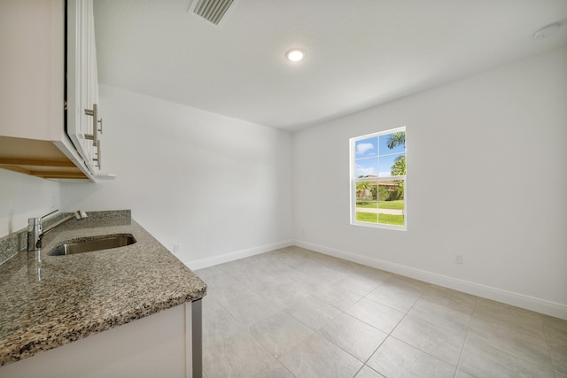 kitchen with white cabinetry, sink, stone countertops, and light tile patterned floors