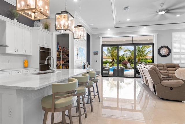 kitchen with crown molding, visible vents, double oven, open floor plan, and a sink