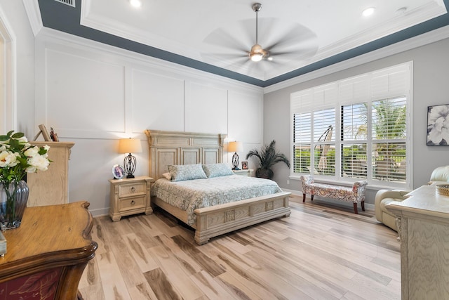 bedroom with a decorative wall, a ceiling fan, baseboards, light wood-style floors, and ornamental molding