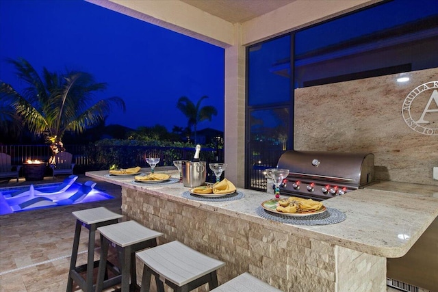 patio at twilight featuring fence, outdoor wet bar, a fenced in pool, and area for grilling