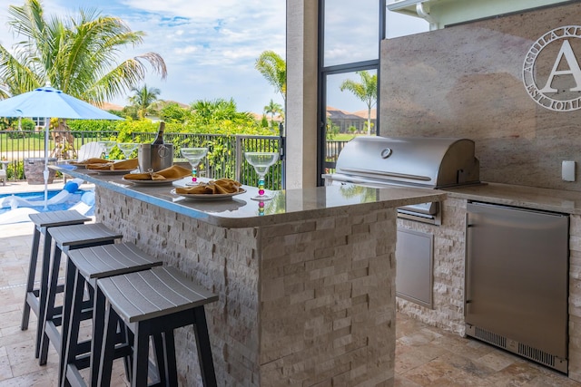 view of patio with a fenced in pool, a grill, fence, exterior kitchen, and outdoor wet bar