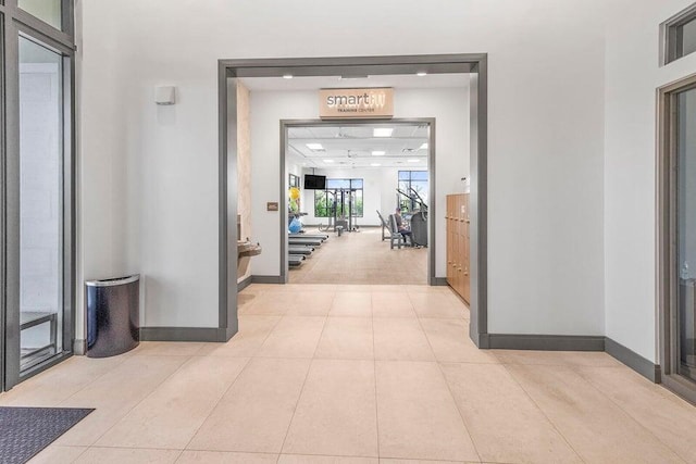 corridor with light tile patterned floors and baseboards