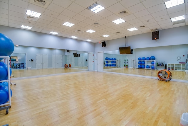 exercise area featuring a high ceiling, visible vents, and wood finished floors