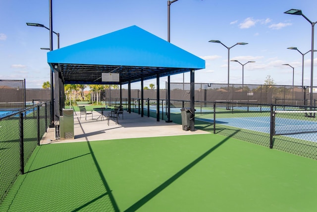 view of property's community with a tennis court and fence